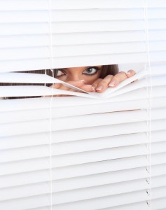 woman-peeking-through-window-blinds